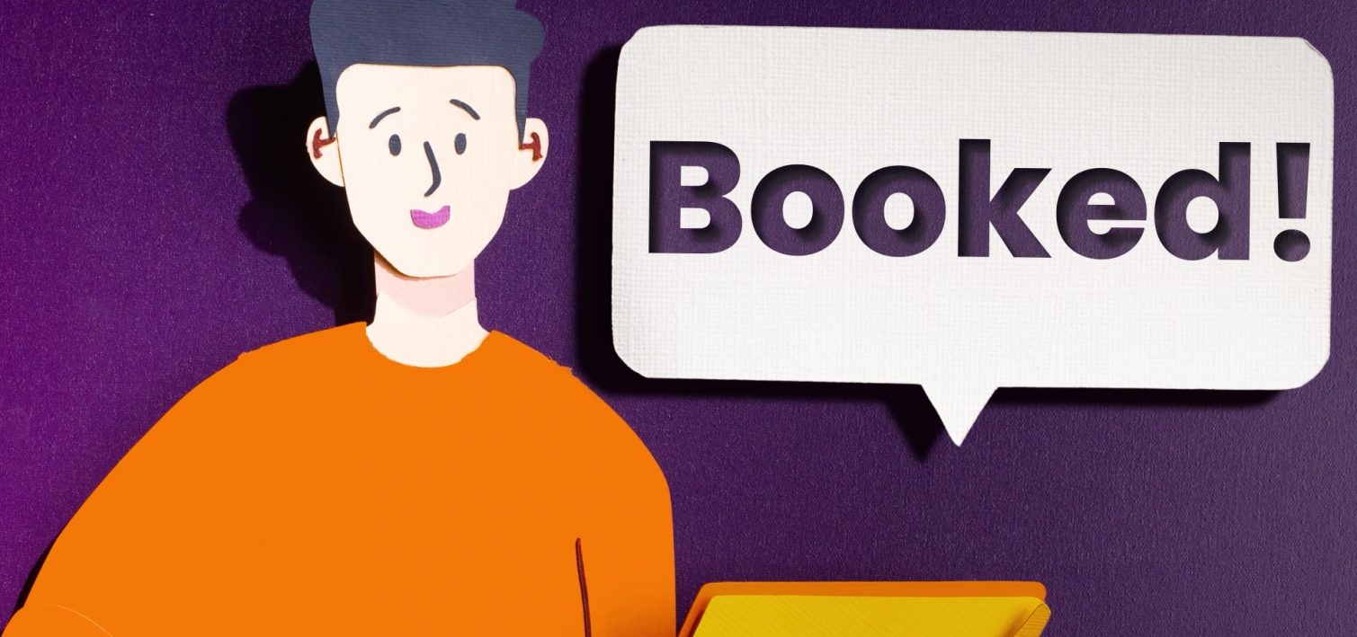A paper host in an orange shirt beside a yellow laptop and a speech bubble reading Booked.