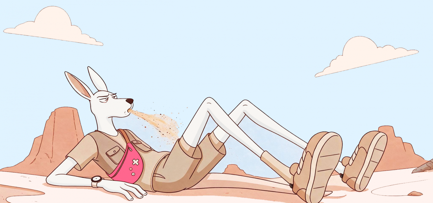 A kangaroo reclines on the sand and spits sand from its mouth.