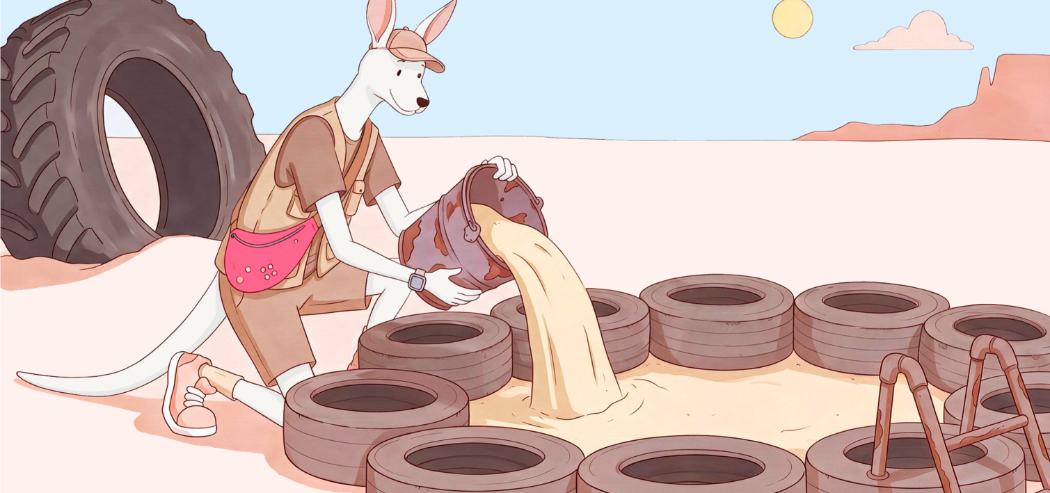A kangaroo pours sand into a circle of tyres in the desert.